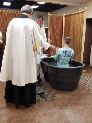 Father John baptizing young man